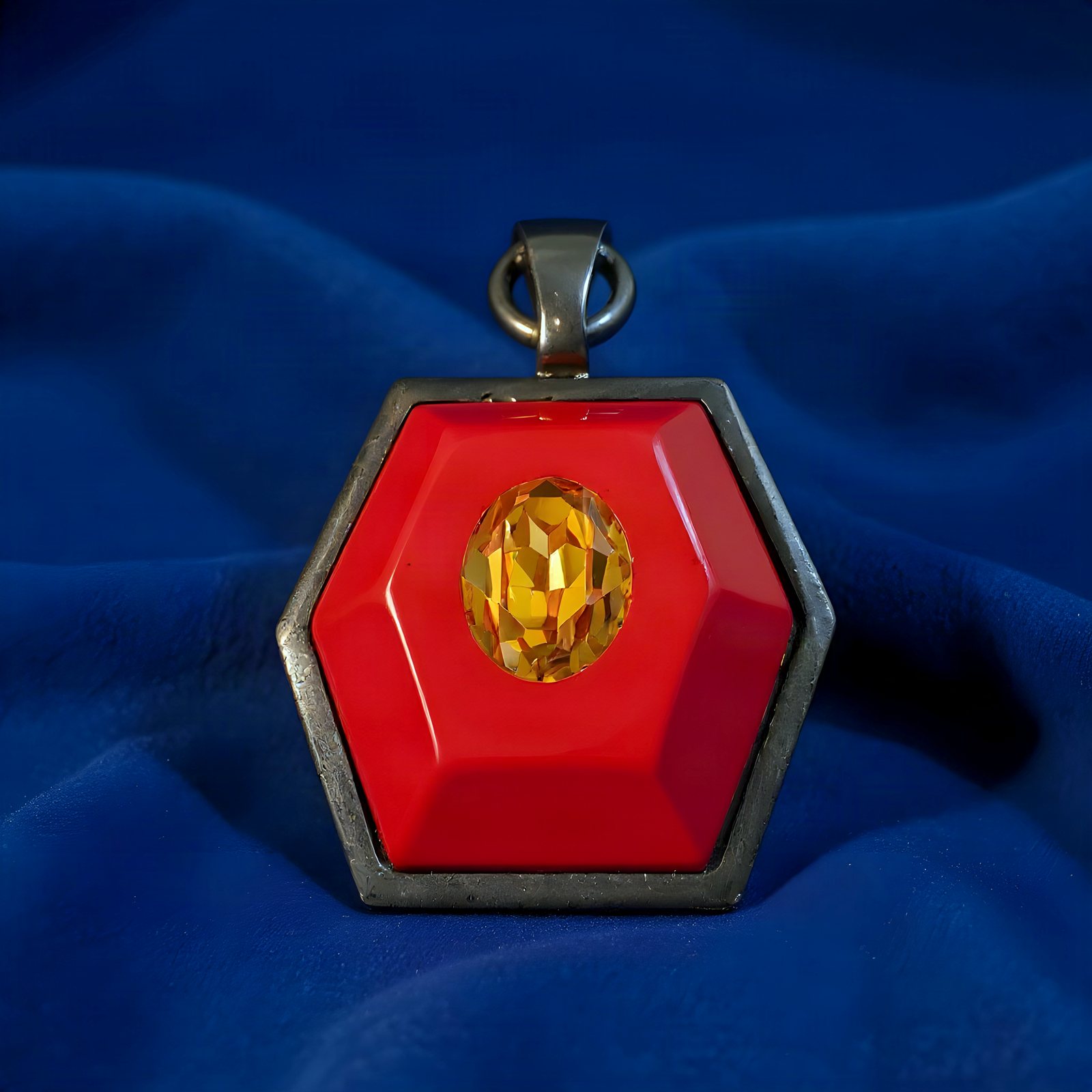 Front of the pendant: red enamel hexagon with an amber oval stone in a gunmetal frame.